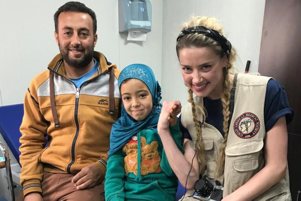 Actress Amber Heard is seen with 12-year-old Weam and her father at a medical center run by the Syrian American Medical Society (SAMS) in Jordan's Zaatari Refugee Camp.