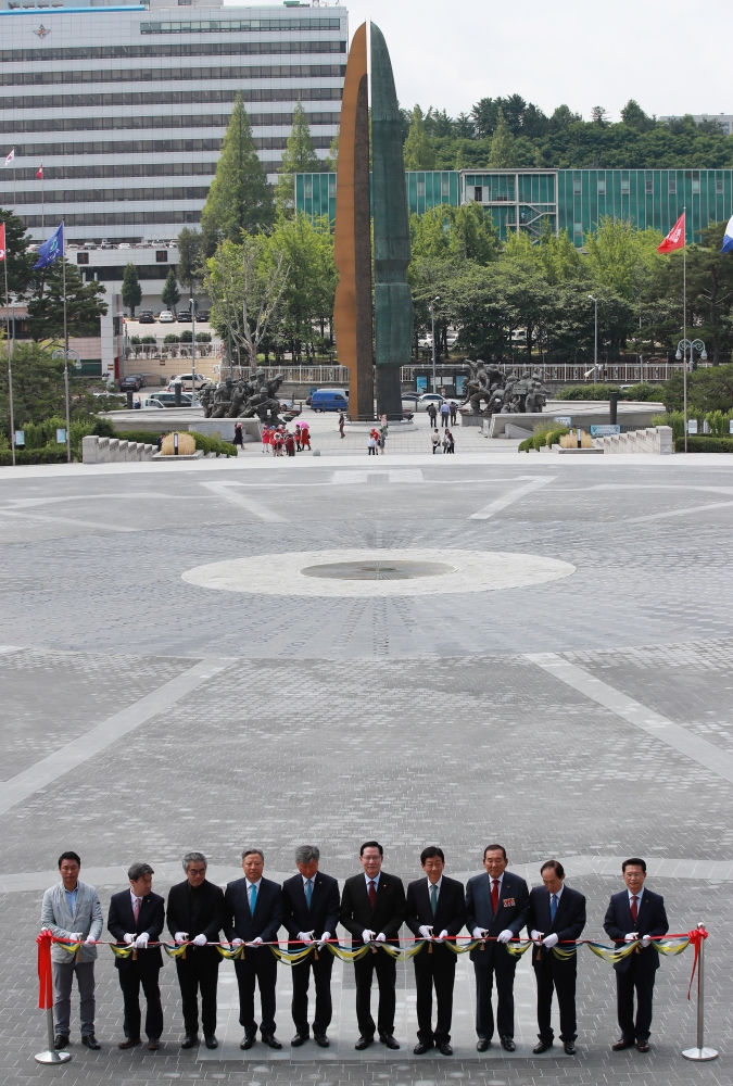 Defense Minister Song Young-moo, fifth right, and other officials hold a tape-cutting ceremony for the reopening of the Peace Plaza at the War Memorial of Korea in Seoul, South Korea, on Wednesday. — EPA