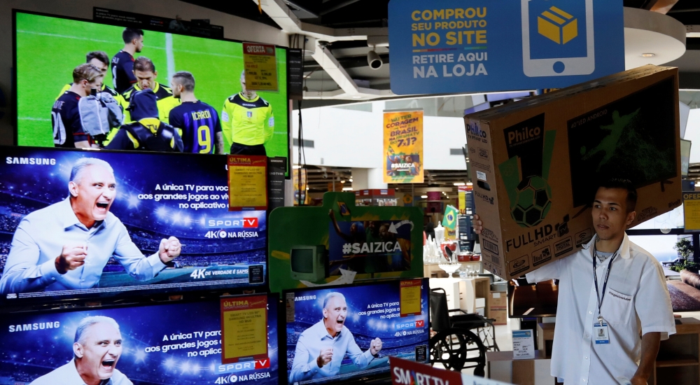 An employee carries a television set in a store in Sao Paulo, Brazil. — Reuters