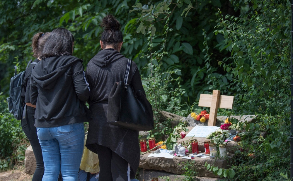 Women stand in front of flowers and candles at a makeshift memorial at the site where 14-year-old Susanna Maria Feldman was allegedly raped and murdered by an Iraqi asylum seeker in Wiesbaden, Germany. — AFP