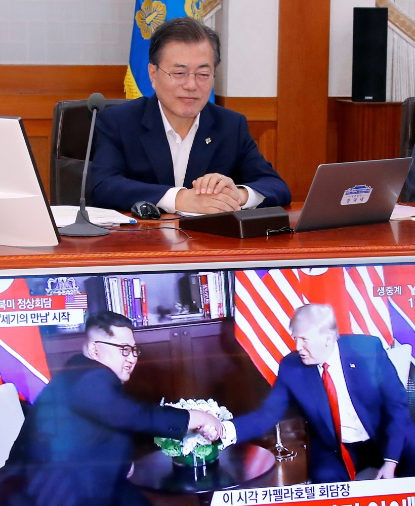South Korean President Moon Jae-in looks at a TV broadcasting a news report on summit between the US and North Korea during a cabinet meeting at the Presidential Blue House in Seoul on Tuesday.  — Reuters
