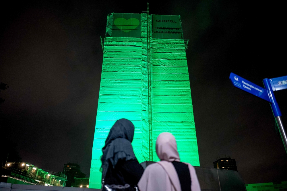 Members of the public hold a vigil and commemoration near Grenfell Tower in west London at midnight on Wednesday to honor the 71 people who died when a fire ripped through the Grenfell tower block in London one year ago. — AFP