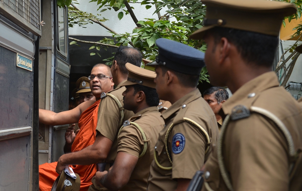 Sri Lankan guards escort firebrand Buddhist monk Galagodaatte Gnanasara after he was sentenced to six months in jail by a magistrate in Homagama on Thursday. — AFP