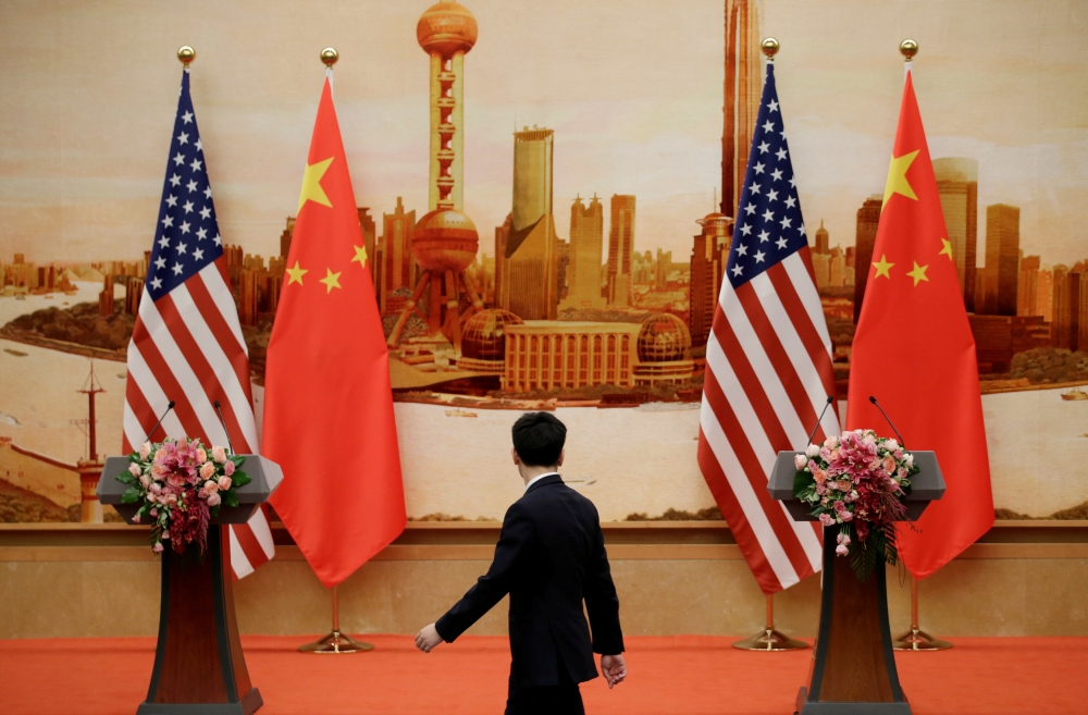 File photo shows a staff member walks past US and Chinese flags placed for a joint news conference by US Secretary of State Mike Pompeo and Chinese Foreign Minister Wang Yi at the Great Hall of the People in Beijing, China, on Thursday. — Reuters