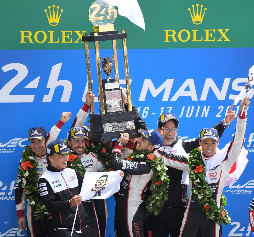 Toyota TS050 Hybrid LMP1's drivers Spain's Fernando Alonso, Japan's Kazuki Nakajima and Switzerland's Sebastien Buemi and Toyota TS050 Hybrid LMP1 drivers Mike Conway, Kamui Kobayashi and Jose Maria Lopez celebrate on the podium after winning the 86th edition of the 24h du Mans car endurance race in Le Mans, western France, Sunday. — AFP