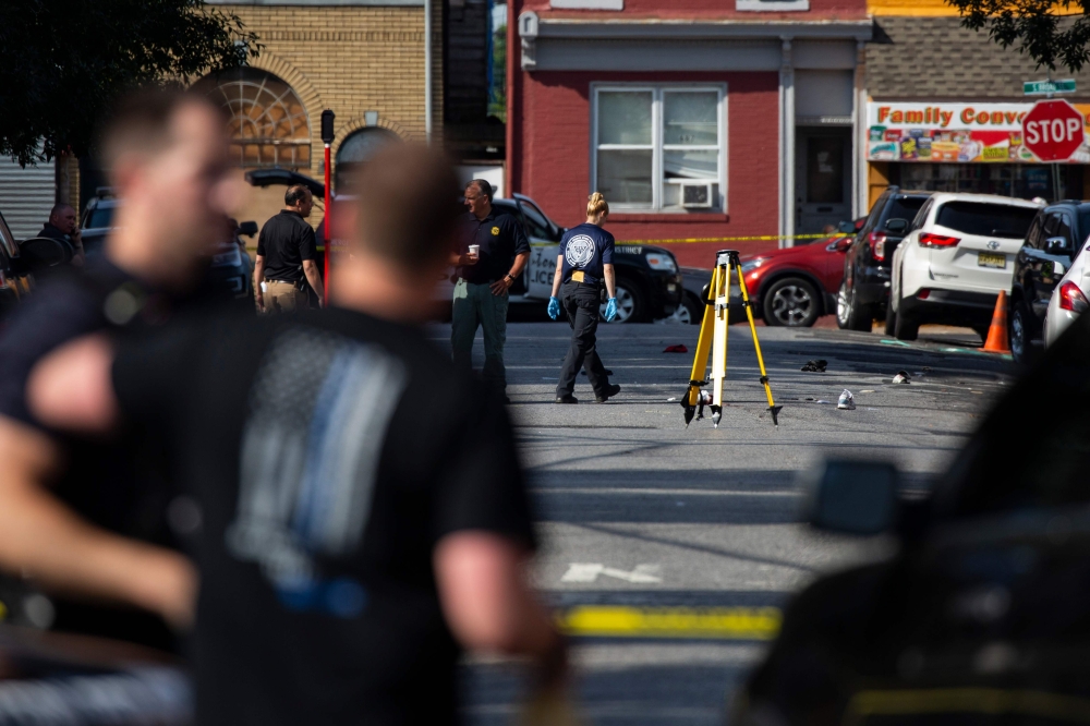 Police officers inspect the crime scene at the Roebling Market on Sunday, the morning after a shooting at an all-night art festival injured 20 people and left one suspect dead in Trenton, New Jersey. — AFP