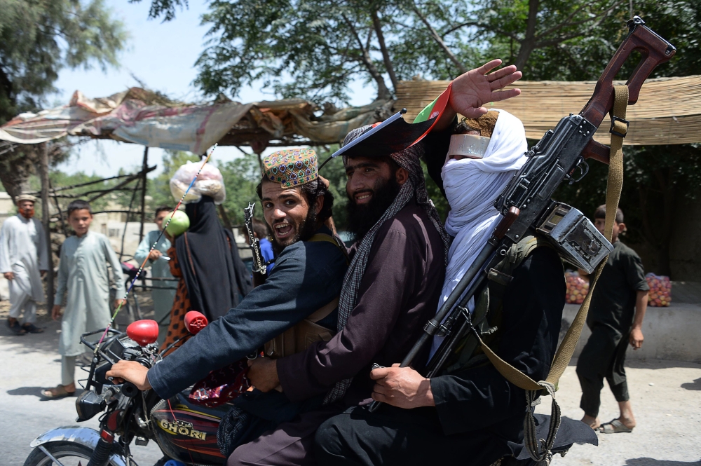 Afghan Taliban militants ride a motorbike as they took to the street to celebrate ceasefire on the second day of Eid in the outskirts of Jalalabad on Saturday. — AFP