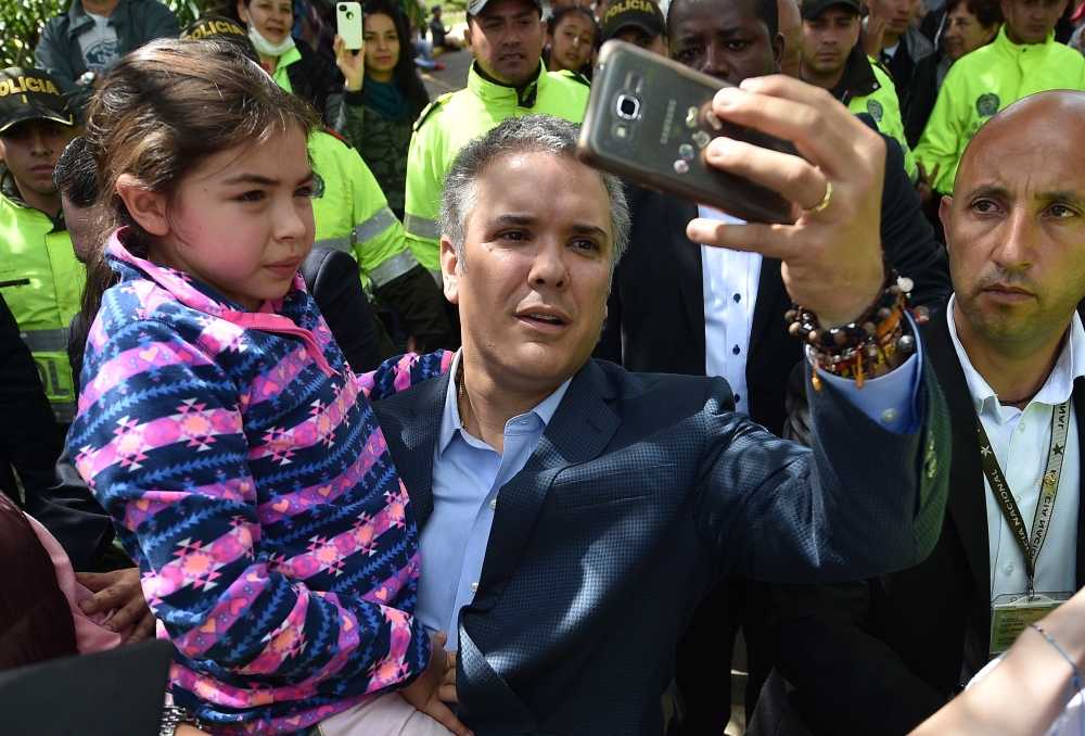 Colombia’s presidential candidate for Colombia’s Democratic Center Party Ivan Duque takes a selfie with a girl after casting his vote during the presidential runoff election in Bogota on Sunday. — AFP