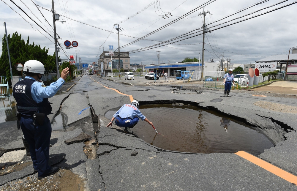Police check a collapsed road following an earthquake in Takatsuki, north of Osaka prefecture, Japan, on Monday. — AFP