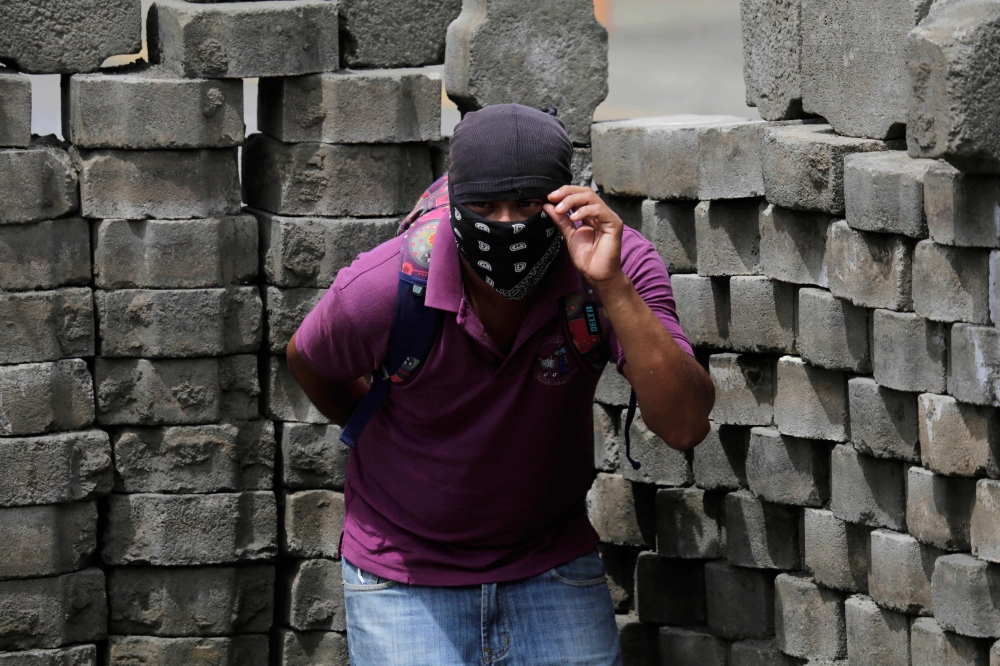 An anti-government demonstrator takes cover behind a barricade, during clashes with riot police and members of the Sandinista youth, in Masaya some 35 km from Managua, on Tuesday. — AFP