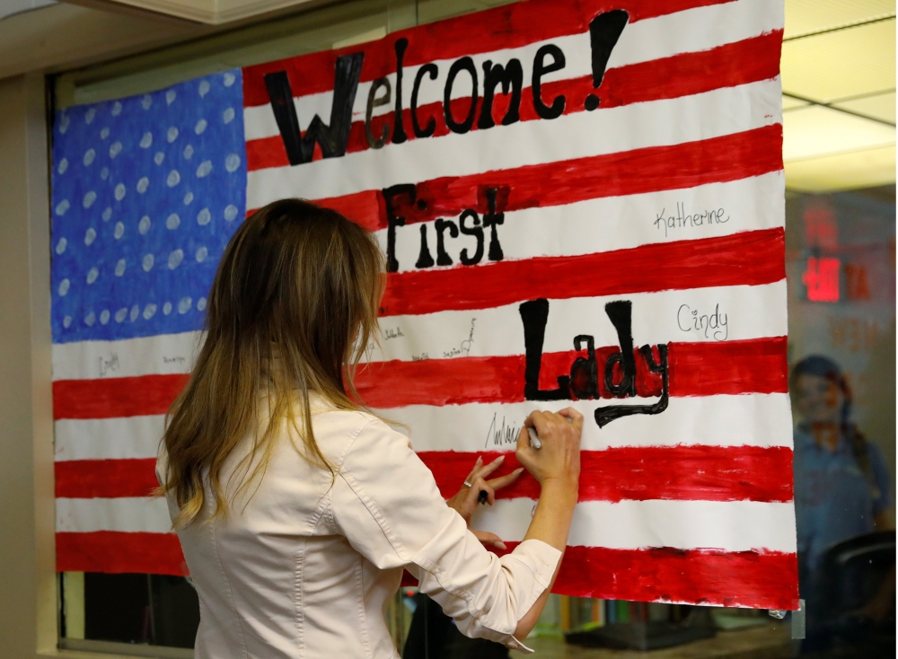 US first lady Melania Trump signs a US flag while touring the Lutheran Social Services of the South 