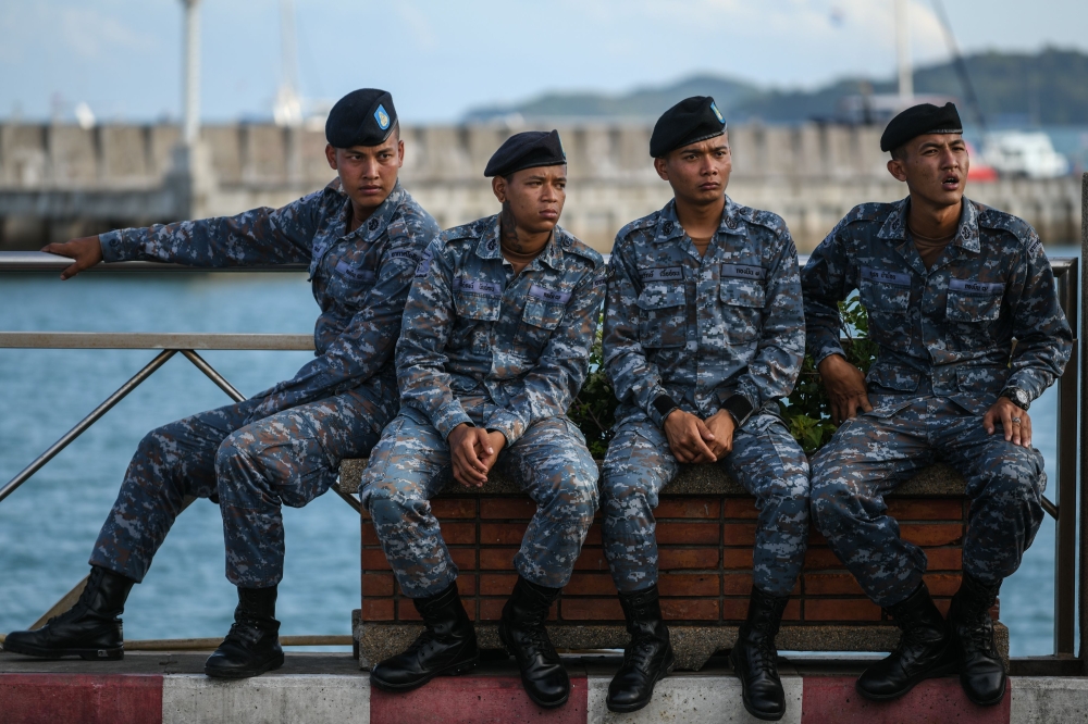 Members of the Royal Thai Air Force rest at Chalong pier in Phuket on Friday, as rescue operations continue nearby for missing tourists following a boating accident on Thursday. — AFP