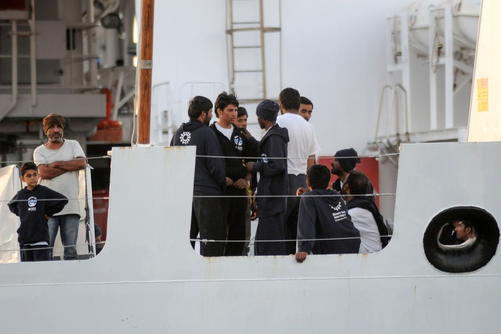 Migrants stand on the bridge of Italy’s Diciotti coast guard vessel carrying 67 asylum seekers berthed at Trapani port on Thursday. — AFP