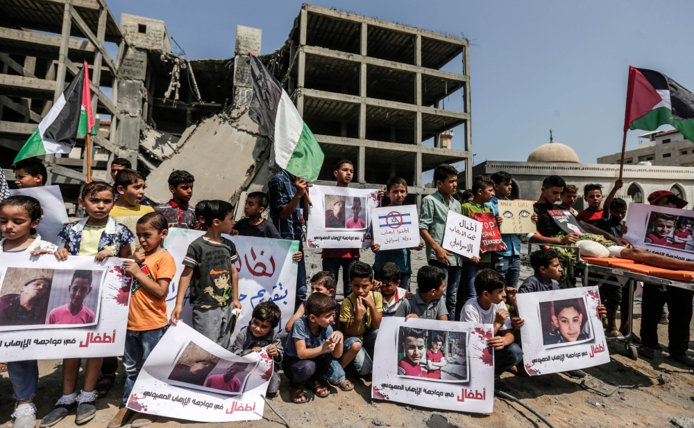 Palestinian youths and children demonstrate with Palestinian flags in Gaza City on Sunday outside a building that was struck by an Israeli air raid the day before. Israel's military said it had launched air strikes targeting Hamas in the Gaza Strip on July 14, as rockets and mortars were lobbed into southern Israel from the blockaded Palestinian enclave. — AFP