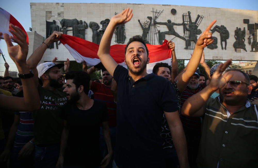 Iraqis holding national flags demonstrate against unemployment in the capital Baghdad's Tahrir Squareon July 14, 2018. Two demonstrators were killed in southern Iraq, officials said, as protests against unemployment spread today from the port city of Basra to other parts of the country including Baghdad. / AFP / AHMAD AL-RUBAYE
