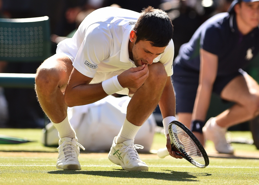 Serbia's Novak Djokovic eats some grass from the court as he celebrates after beating South Africa's Kevin Anderson in their men's singles final match of the 2018 Wimbledon Championships at The All England Lawn Tennis Club in Wimbledon, southwest London, on Sunday. - AFP