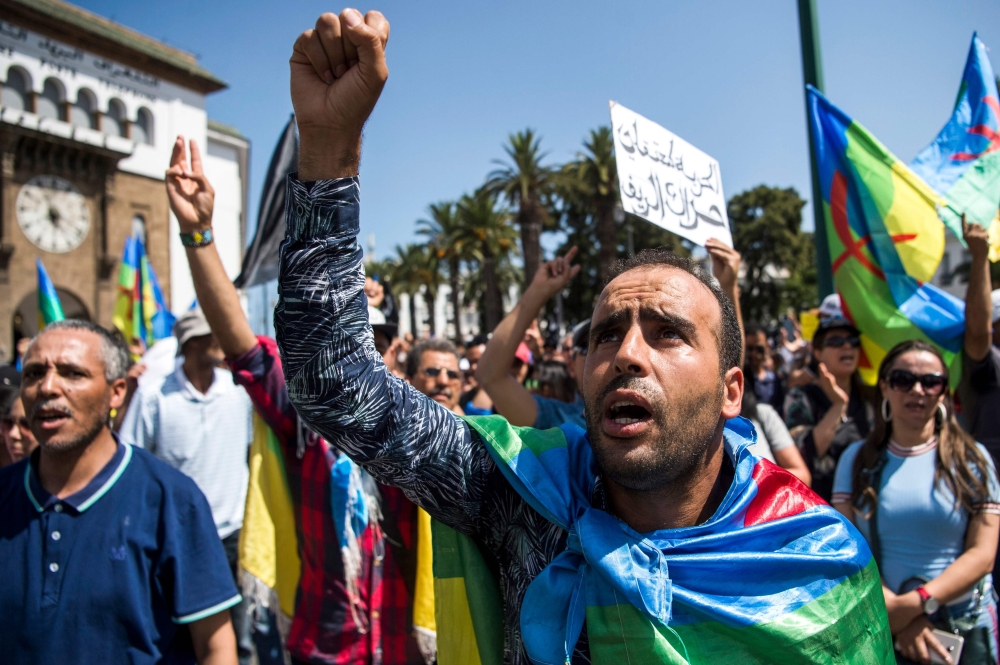 A Moroccan draped in the Berber, or Amazigh, flag shouts slogans while marching during a protest against the jailing of Al-Hirak al-Shaabi or 