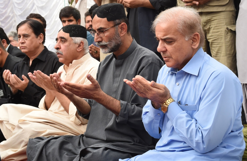 Shahbaz Sharif, right, the younger brother of ousted Pakistani Prime Minister Nawaz Sharif, and head of Pakistan Muslim League-Nawaz (PML-N) prays along with Lashkar Raisani, second right, the brother of Siraj Raisani, a candidate of provincial seat who was killed on July 13 suicide bombing in Mastung during an election campaign, in Quetta on Sunday. — AFP