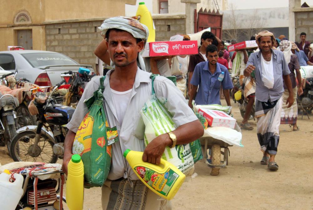 Displaced Yemenis from Hodeidah receive food aid from a Japanese NGO in the northern district of Abs, in Hajjah province. — AFP
