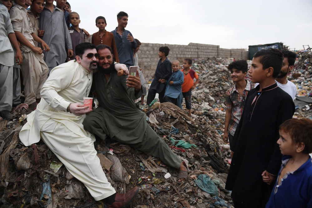 Ayaz Memon Motiwala (left), 42, an independent candidate contesting a seat in the National Assembly and two seats for the provincial Sindh Assembly, poses with a supporter at a garbage dump during an election rally in Karachi. 