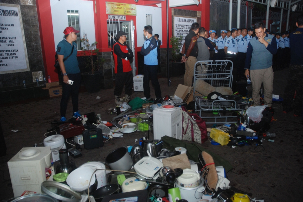 Indonesian officials stand near home appliances that were collected from inmates at the Sukamiskin jail in Bandung on Sunday. — AFP