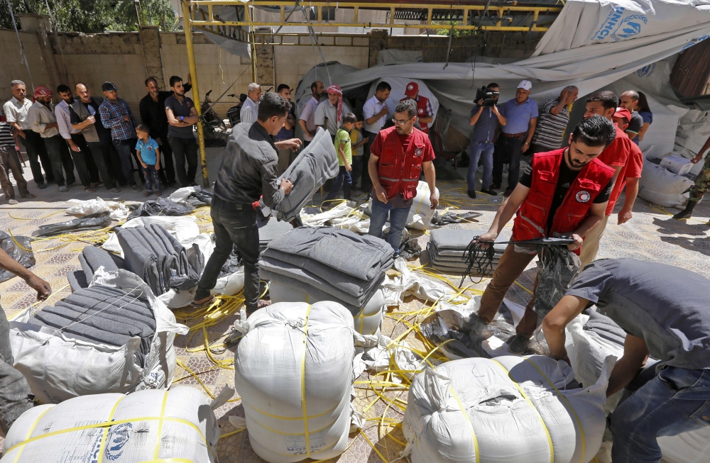 Members of the Syrian Arab Red Crescent distribute humanitarian aid to residents of the town of Douma as part of a humanitarian assistance provided by France in the region of Eastern Ghouta, Syria, on Thursday. — AFP