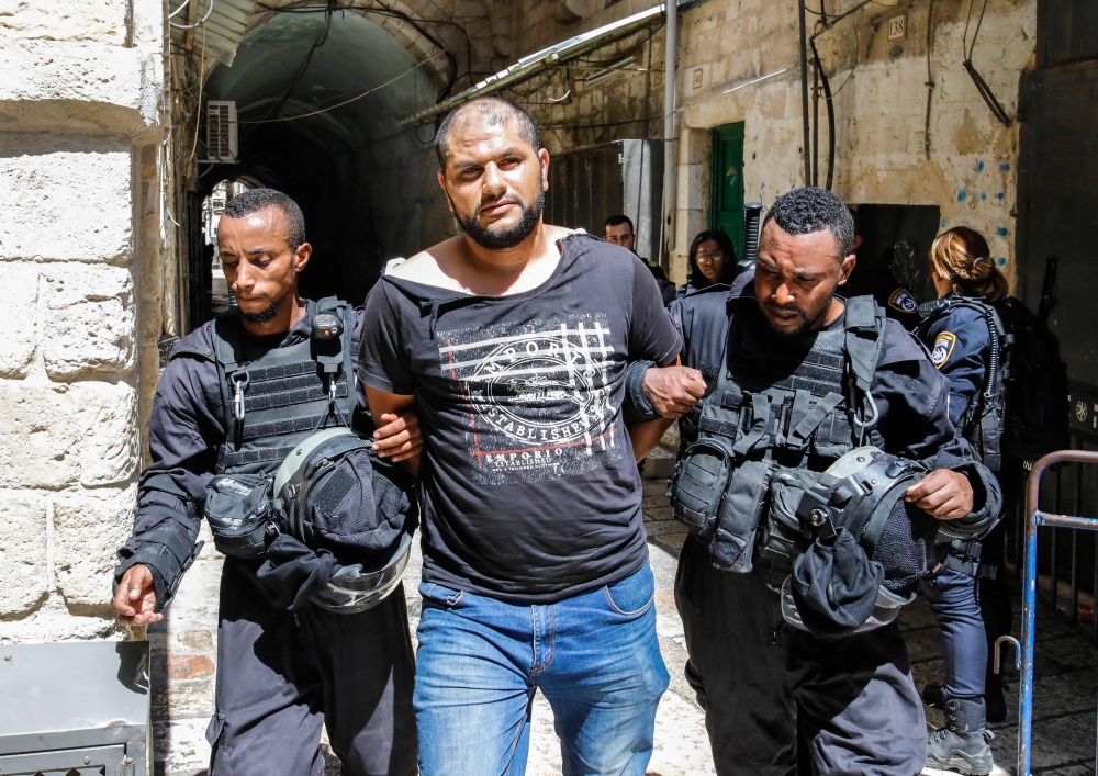 Members of the Israeli security forces take into custody a Palestinian protester who was arrested during clashes at the Aqsa mosque compound in the Old City of Jerusalem on Friday. — AFP