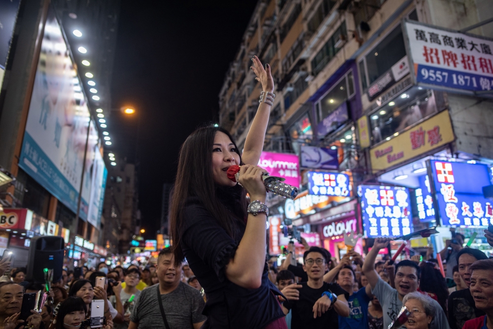 A singer waves to supporters during a farewell performance in the pedestrian zone of Sai Yeung Choi Street South in Mong Kok, Hong Kong on Sunday night. - AFP