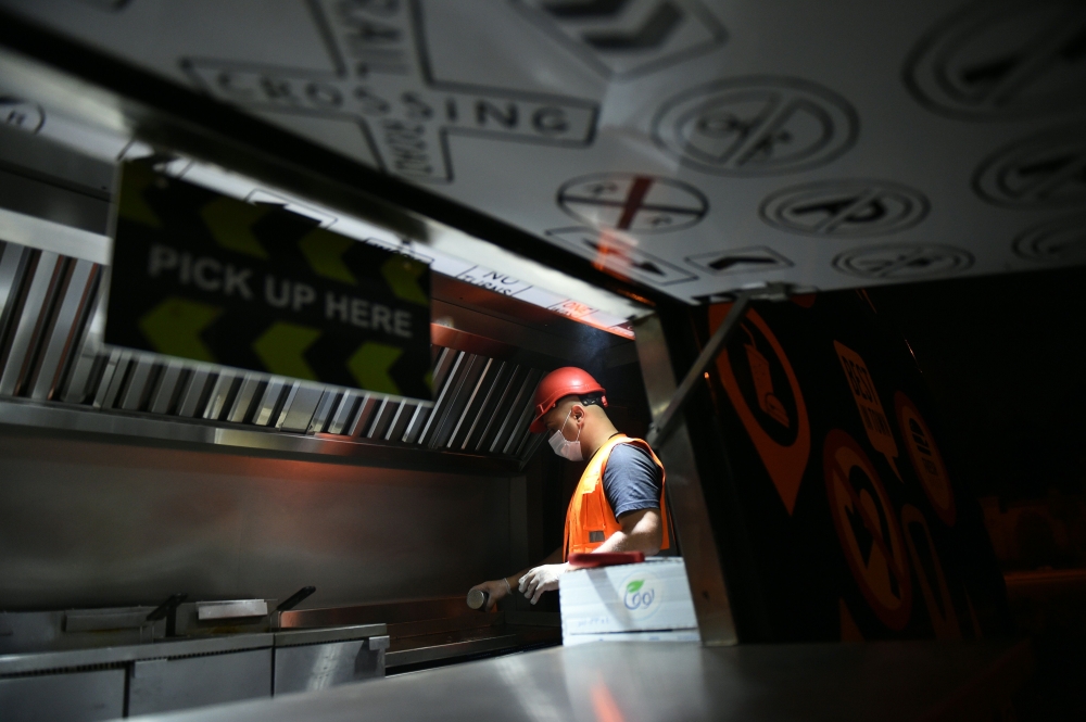 Bader Al-Ajmi, owner of “One Way Burger”, serving customers from his truck at a main street in Riyadh. — AFP
