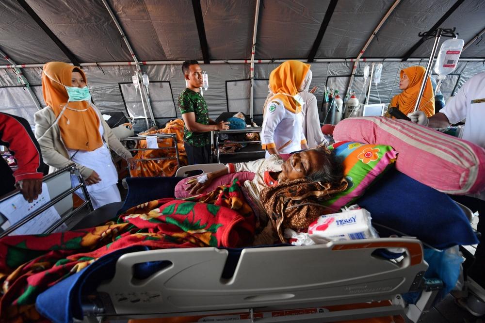 Patients receive medical help at a makeshift ward set up outside the Moh. Ruslan hospital in Mataram on the Indonesian island of Lombok on August 6, 2018, the morning after a 6.9 magnitude stuck the area. — AFP