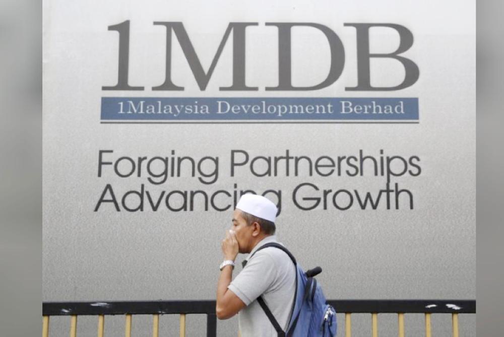 File photo shows a man covering his mouth as he walks past a 1 Malaysia Development Berhad (1MDB) billboard at the funds flagship Tun Razak Exchange development in Kuala Lumpur, Malaysia. — Reuters