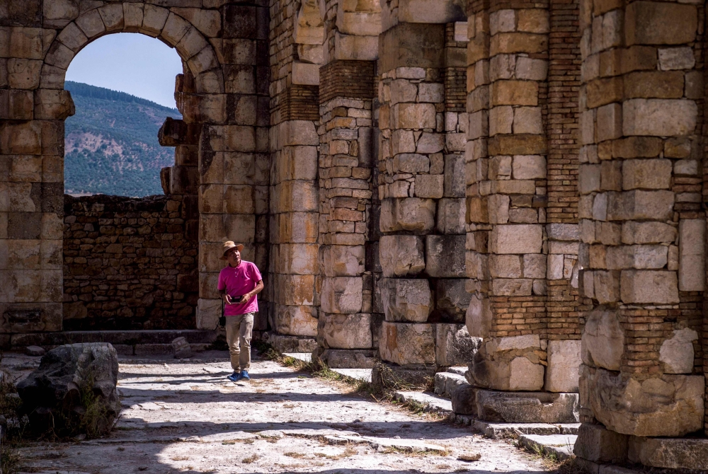 A tourist walks through the ruins of the ancient Roman site of Volubilis, near the town of Moulay Idriss Zerhounon in Morocco's north central Meknes region. Situated in the center of a fertile plain at the foot of Mount Zerhoun, the towering remains of Morocco's oldest Roman site, Volubilis, were long neglected. But after decades of looting and decay, custodians of the now closely guarded ancient city are turning the page and attracting back tourists. — AFP