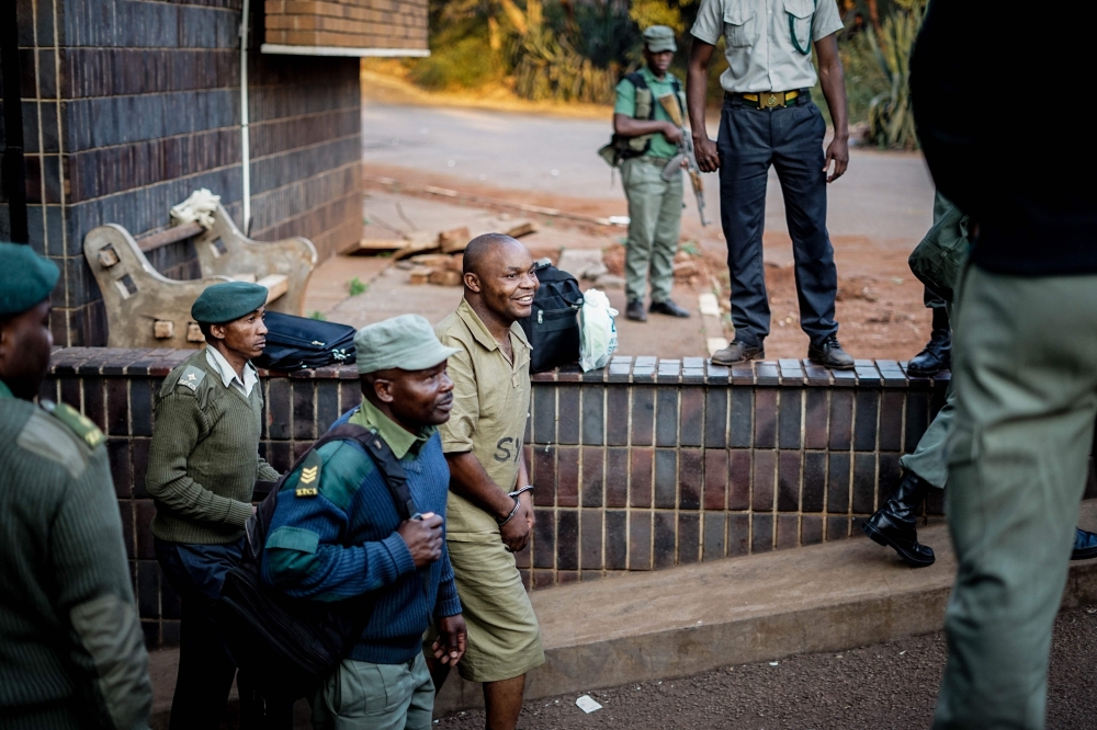 A supporter of the opposition Movement for Democratic Change (MDC) Alliance is escorted to a waiting prison truck outside the magistrate's court in Harare on Tuesday after many MDC supporters were arrested following a post election violence. — AFP