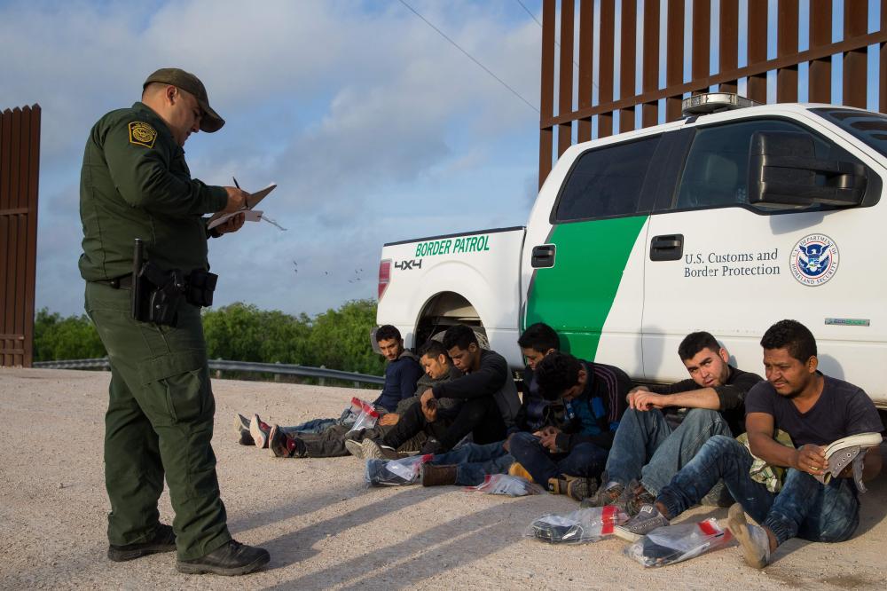 A Border Patrol agent apprehends illegal immigrants shortly after they crossed the border from Mexico into the United States in the Rio Grande Valley Sector near McAllen, Texas, in this March 26, 2018 file photo. — AFP
