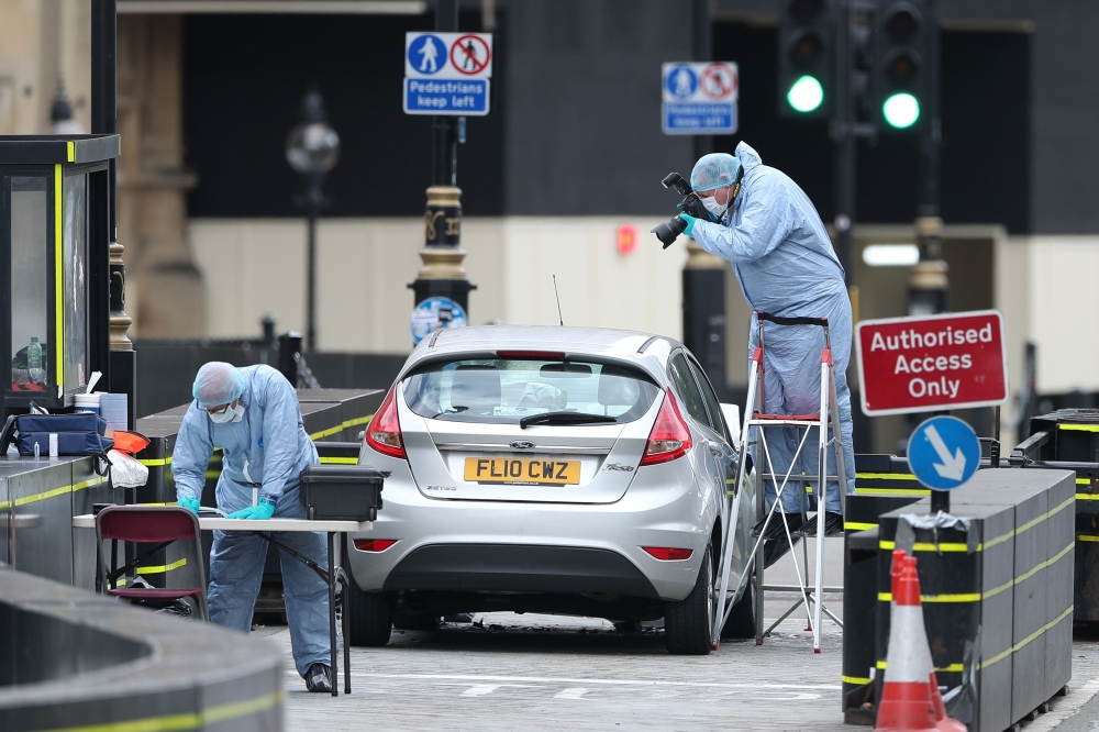 Police forensics officers work around a silver Ford Fiesta car that was driven into a barrier at the Houses of Parliament in central London on Tuesday. — AFP