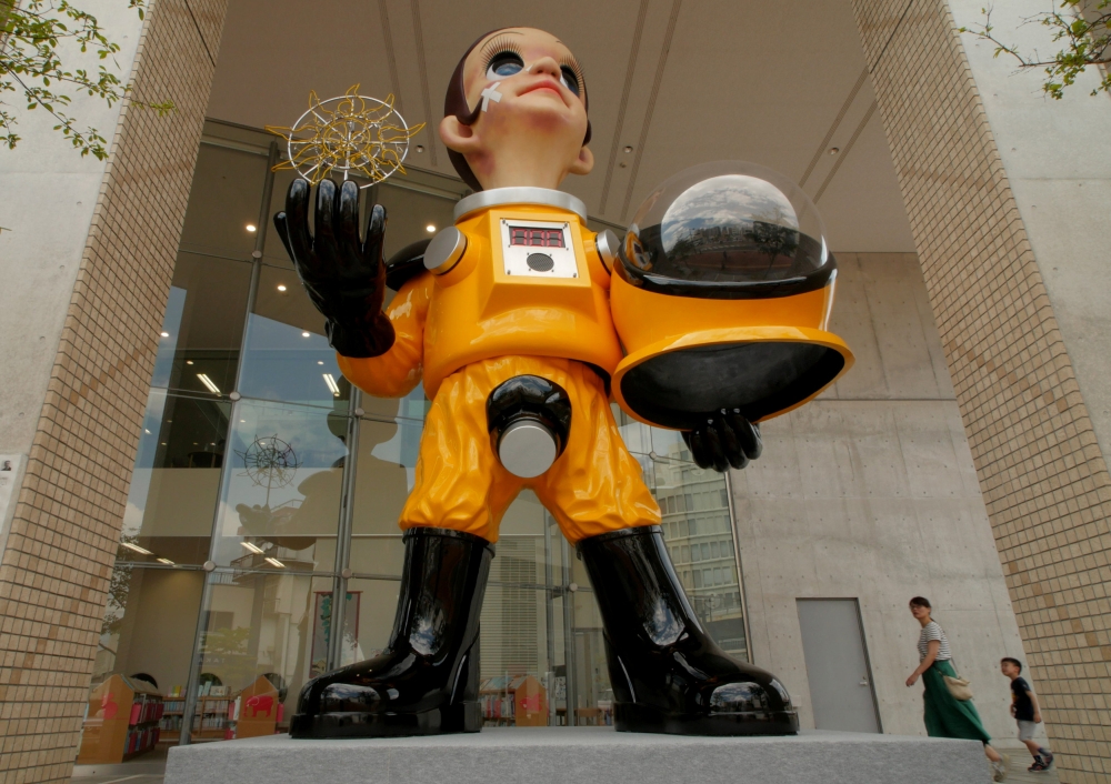 People walk by a statue of a child wearing what appears to be a hazardous material suit in Fukushima, Japan, on Tuesday. — Reuters