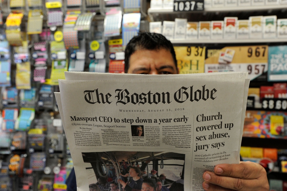 Phillip Minias, 46, owner of Snax Express, reads the Boston Globe,  in Boston, Massachusetts, on Wednesday. — AFP
