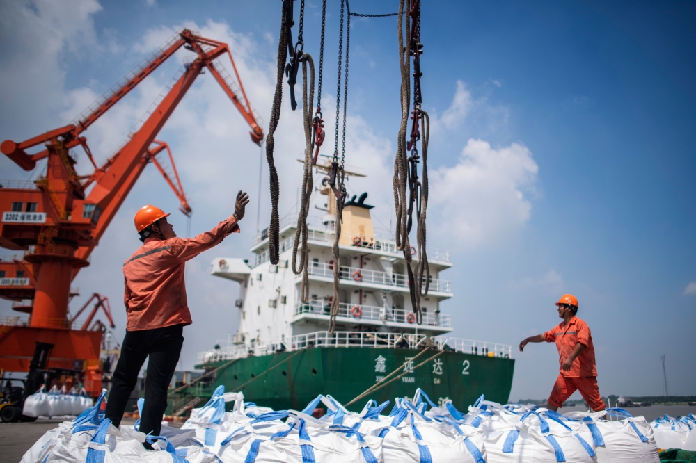 This file picture shows workers unloading bags of chemicals at a port in Zhangjiagang in China's eastern Jiangsu province.  China will send a senior negotiator to the United States in late August to resume trade talks, the Commerce Ministry said. - AFP