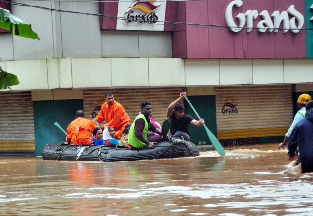 Indian navy and rescue personnel evacuate local residents in an boat at Aluva, in the Indian state of Kerala, on Thursday. — AFP