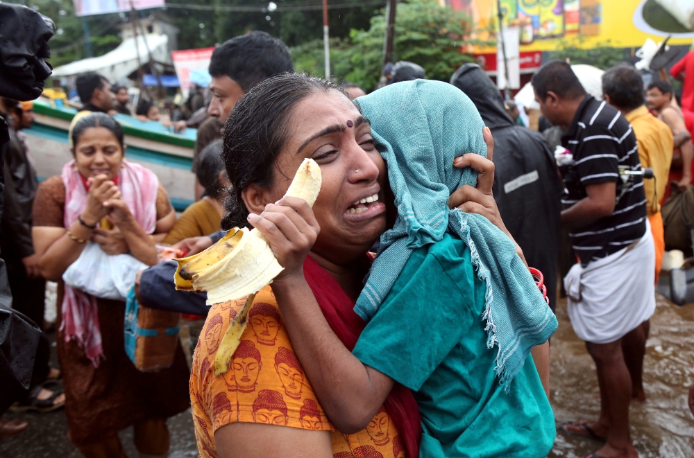 A woman cries as she holds her son after they were evacuated from a flooded area in Aluva in the southern state of Kerala, India, on Saturday. — Reuters