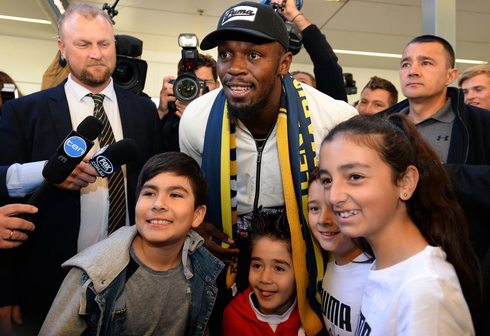Usain Bolt poses for pictures with fans upon arrival at Sydney international airport Saturday. — AFP