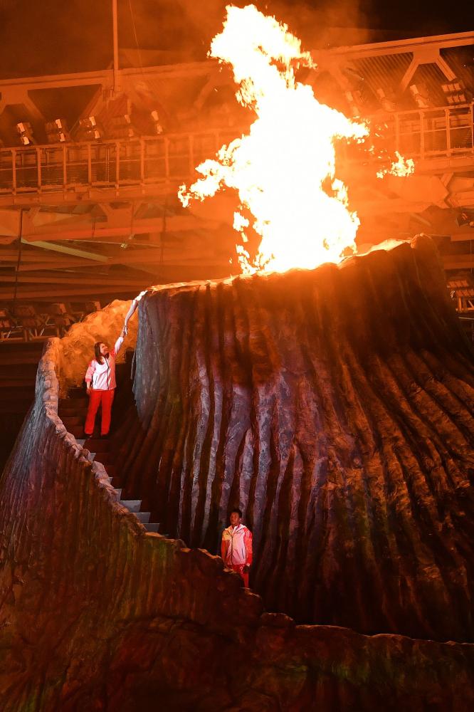 Former Indonesian athlete Susi Susanti (top) lights the cauldron during the opening ceremony of the 2018 Asian Games at the Gelora Bung Karno Stadium in Jakarta Saturday. — AFP