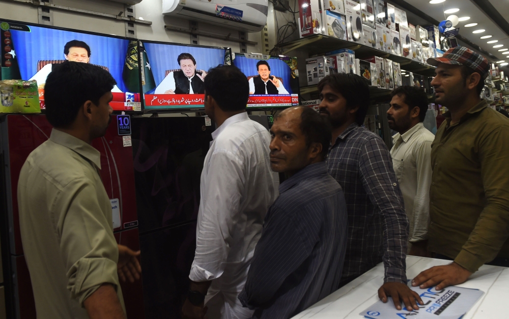Pakistani men gather around a bank of televisions in a store as they watch a broadcast of a speech of newly appointed Pakistani Prime Minister Imran Khan, as he addresses the nation, in Lahore on Sunday. — AFP
