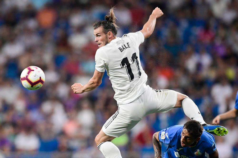 Real Madrid's Gareth Bale (L) challenges Getafe's defender Damian Suarez during the Spanish football league match at the Santiago Bernabeu Stadium in Madrid Sunday. — AFP