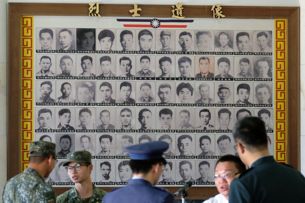 Military staff talk in front of portraits of deceased soldiers during the 60th anniversary of the ‘823 bombardment’ in Kinmen, Taiwan, on Thursday. — AFP