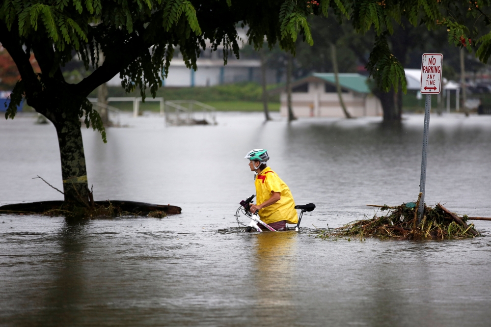 A woman pushes her bicycle through flooding caused by Hurricane Lane in Hilo, Hawaii, on Saturday. — Reuters
