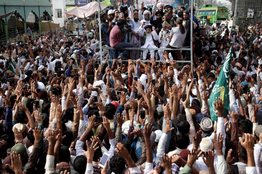 Supporters of the Tehrik-e-Labaik Pakistan (TLP) political party raise their hands as they listen to the speech of their leader during a protest march to condemn the cartoon competition by the Netherlands, in Lahore, Pakistan, on Wednesday. — Reuters