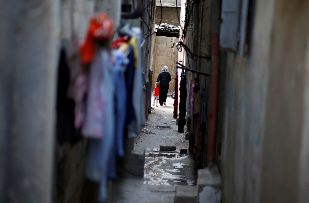 A Palestinian woman walks with her daughter in a narrow alley at Al-Shati refugee camp, in Gaza City, Saturday. — Reuters