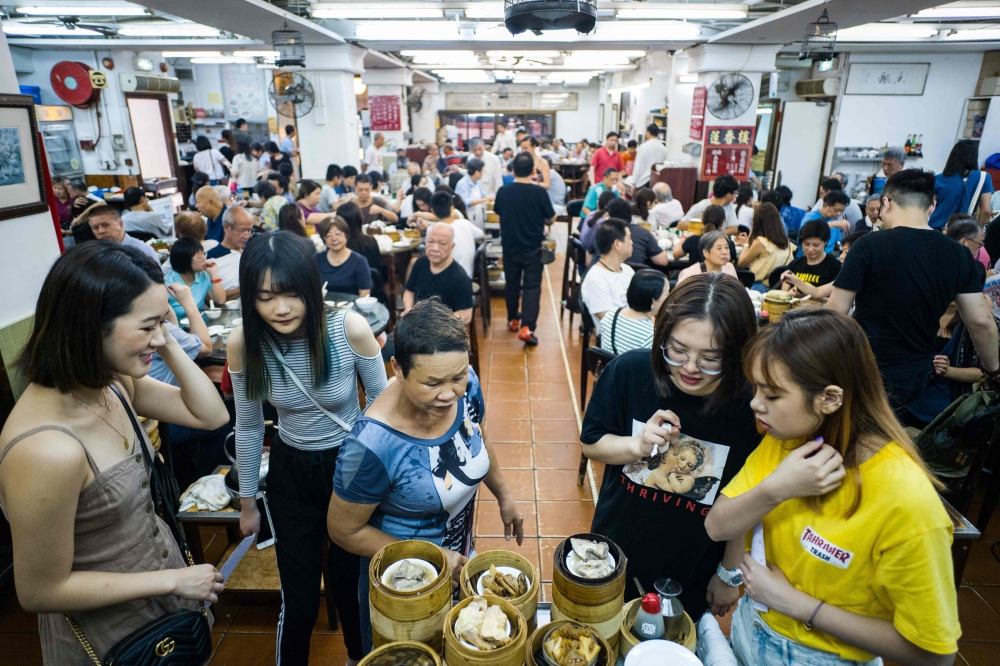 A kitchen worker carries bamboo dim sum steamers in the kitchen of the Lin Heung Tea House in Hong Kong. - AFP