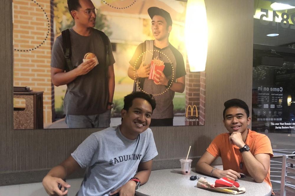 Jevh Maravilla and his friend, Christian, pose beneath their McDonald’s poster from inside a McDonald's restaurant in Pearland, Texas.

